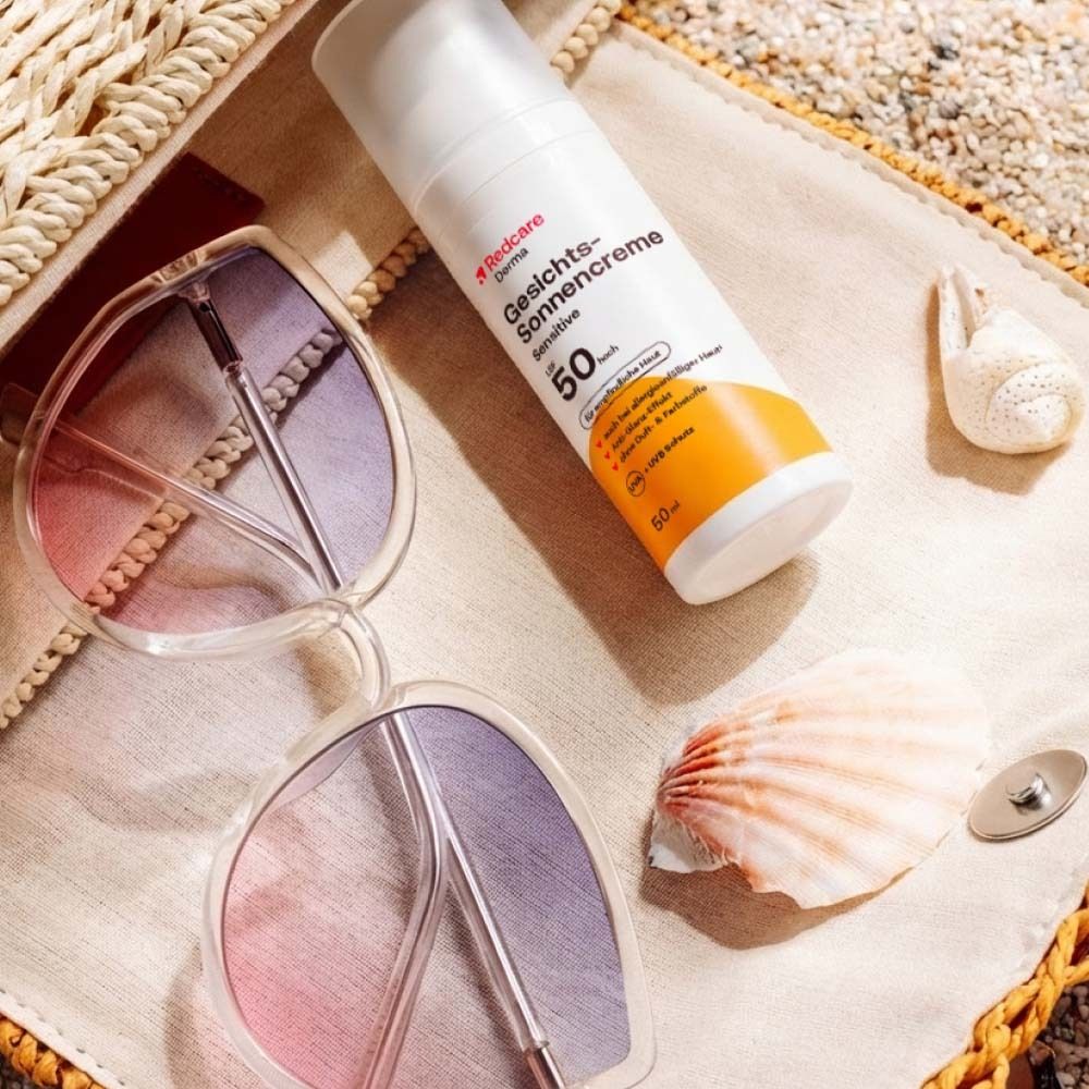 Flacon de crème solaire, lunettes de soleil et coquillage sur un sac de plage. Fond de plage.