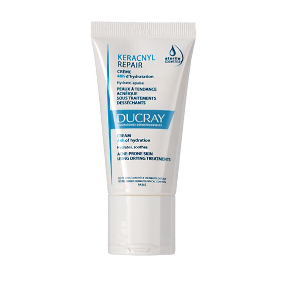 Tube blanc avec texte bleu. Inscription: KERACNYL REPAIR CREME, DUCRAY. Pour peaux à tendance acnéique sous traitements desséchants.