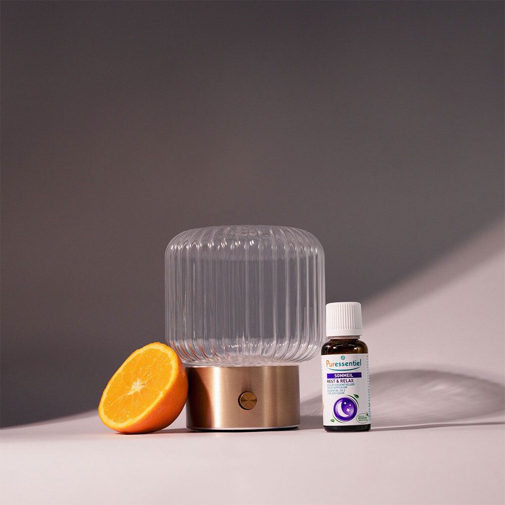 Diffuseur en verre avec base dorée, à côté d'un flacon et d'une tranche d'orange. Inscription: SOMMEIL.