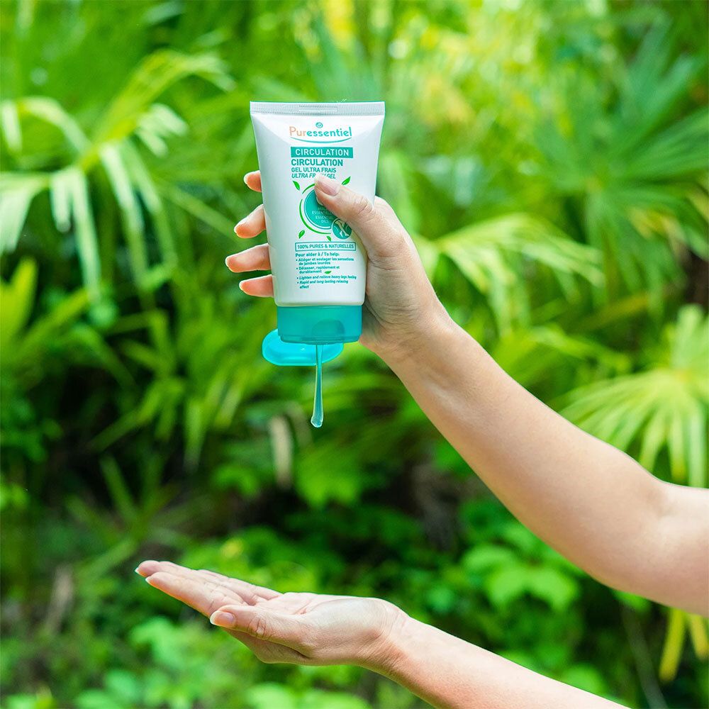 Mains tenant un tube blanc et turquoise. Le produit est pressé hors de l'ouverture.