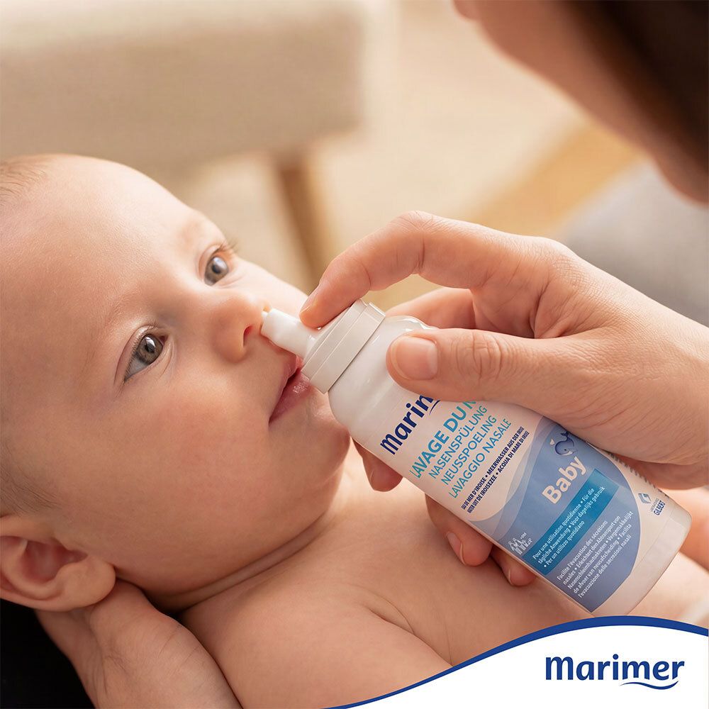 Bébé se fait pulvériser le nez avec un spray. Inscription: Marimer, Lavage du nez. Pour bébé.