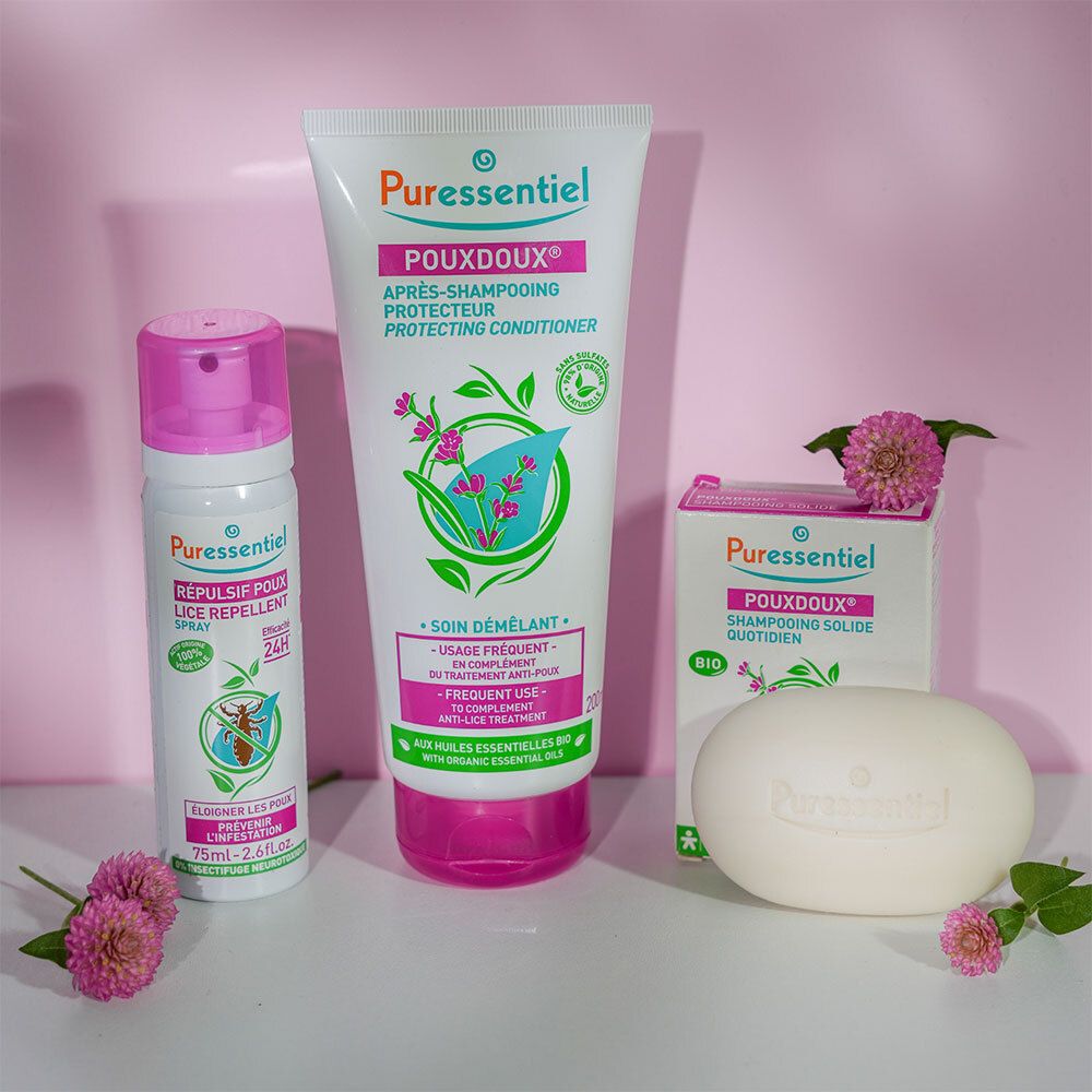 Ensemble de produits: tube, spray, savon et boîte. Tous avec le logo POUXDOUX®. Fond rose.