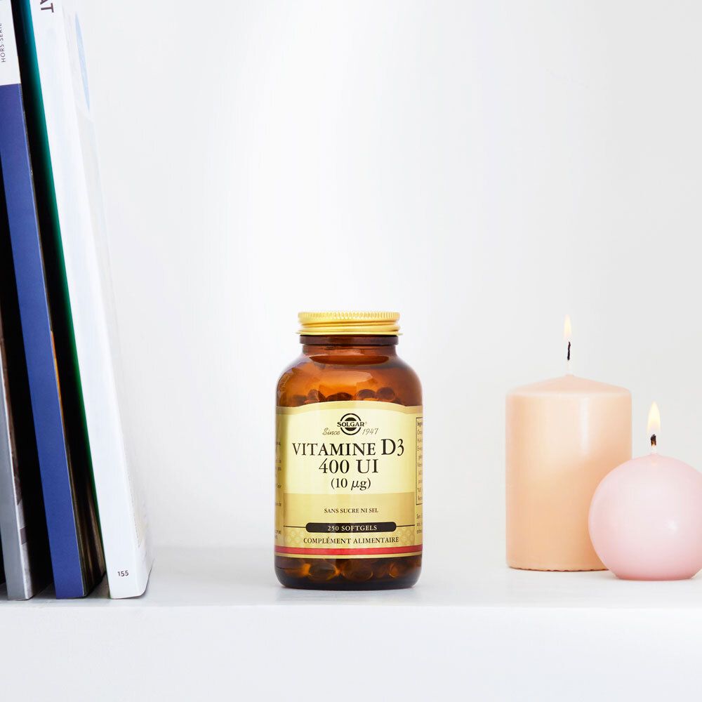 Flacon brun avec bouchon doré sur une étagère. Bougies et livres à côté.