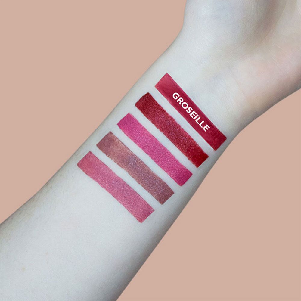 Bras avec cinq couleurs de rouge à lèvres. En haut : GROSEILLE. Différentes nuances de rouge.