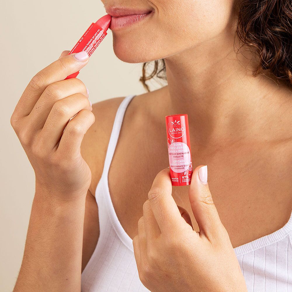 Femme appliquant un stick à lèvres rouge. Un autre stick est tenu. Produit: LAINO Soin des lèvres.