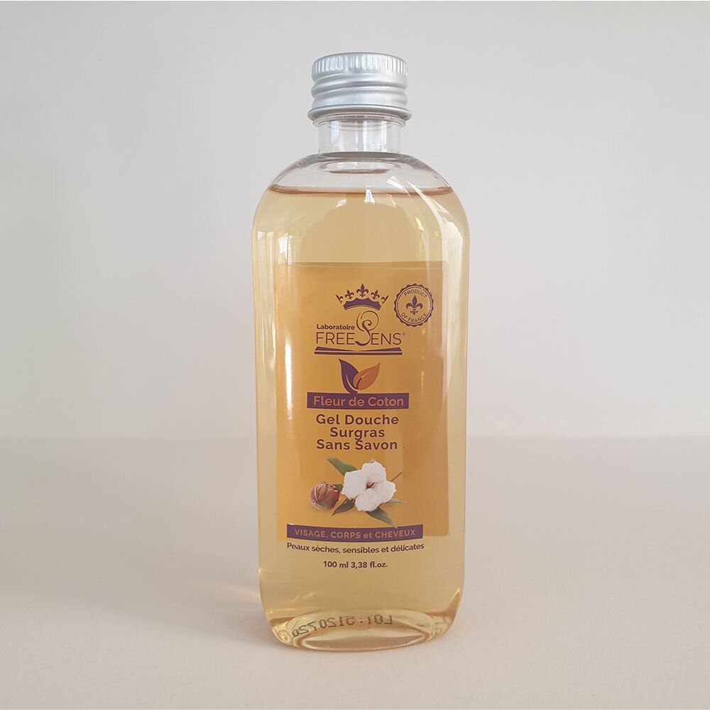 Flacon transparent contenant un liquide jaunâtre. Étiquette avec nom du produit et illustration de fleur de coton. Bouchon argenté.