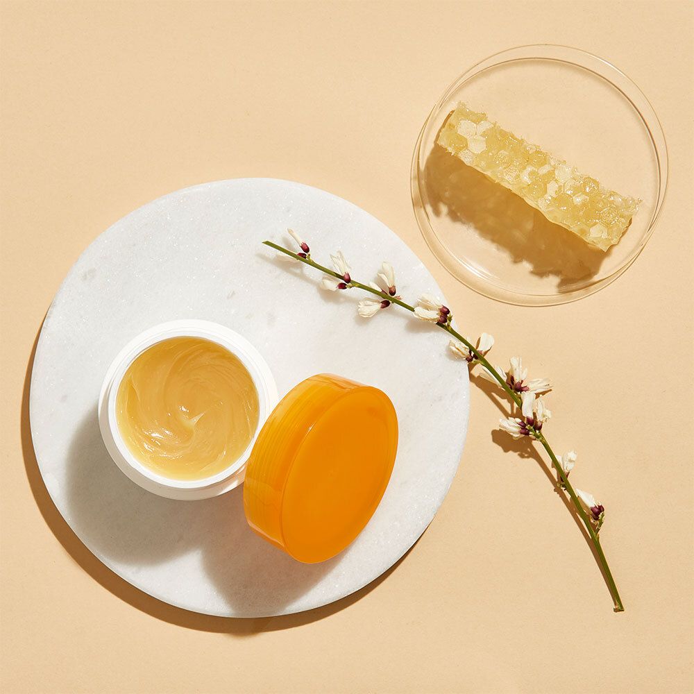 Pot de crème ouvert, crème jaune, à côté d'un rayon de miel et d'une fleur sur fond blanc. Inscription: Alvadiem.