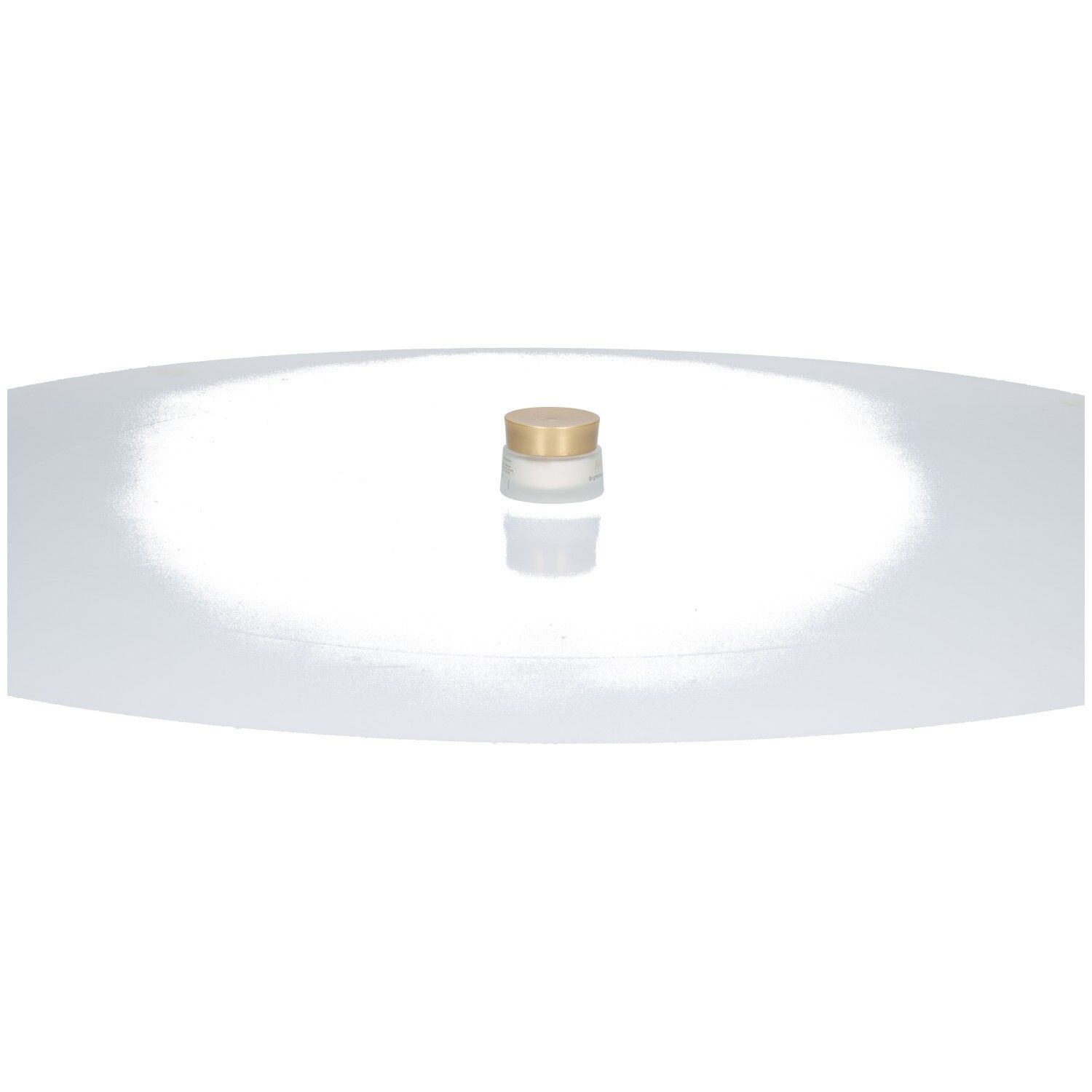 Un pot de crème avec un couvercle doré, sur une surface blanche.