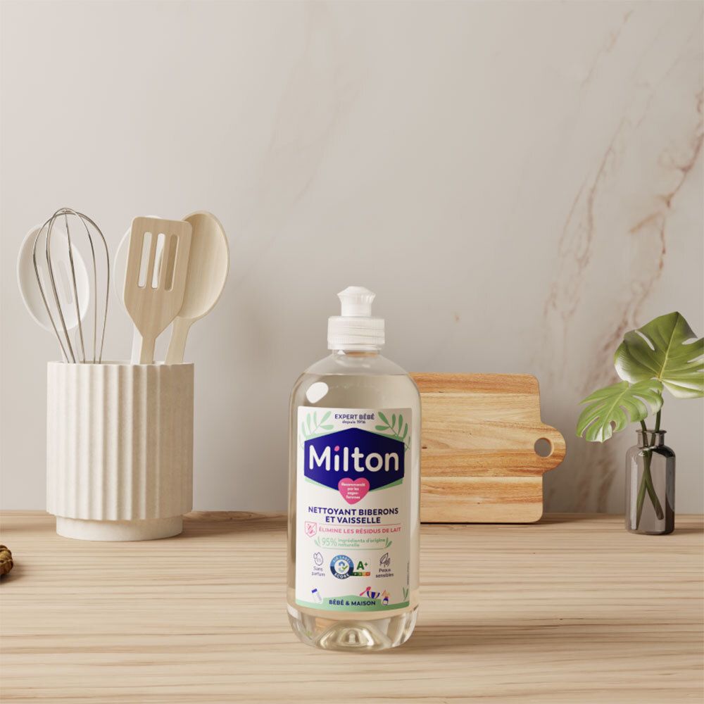 Nettoyant Milton pour biberons sur une surface en bois, près d'ustensiles de cuisine et d'une plante.