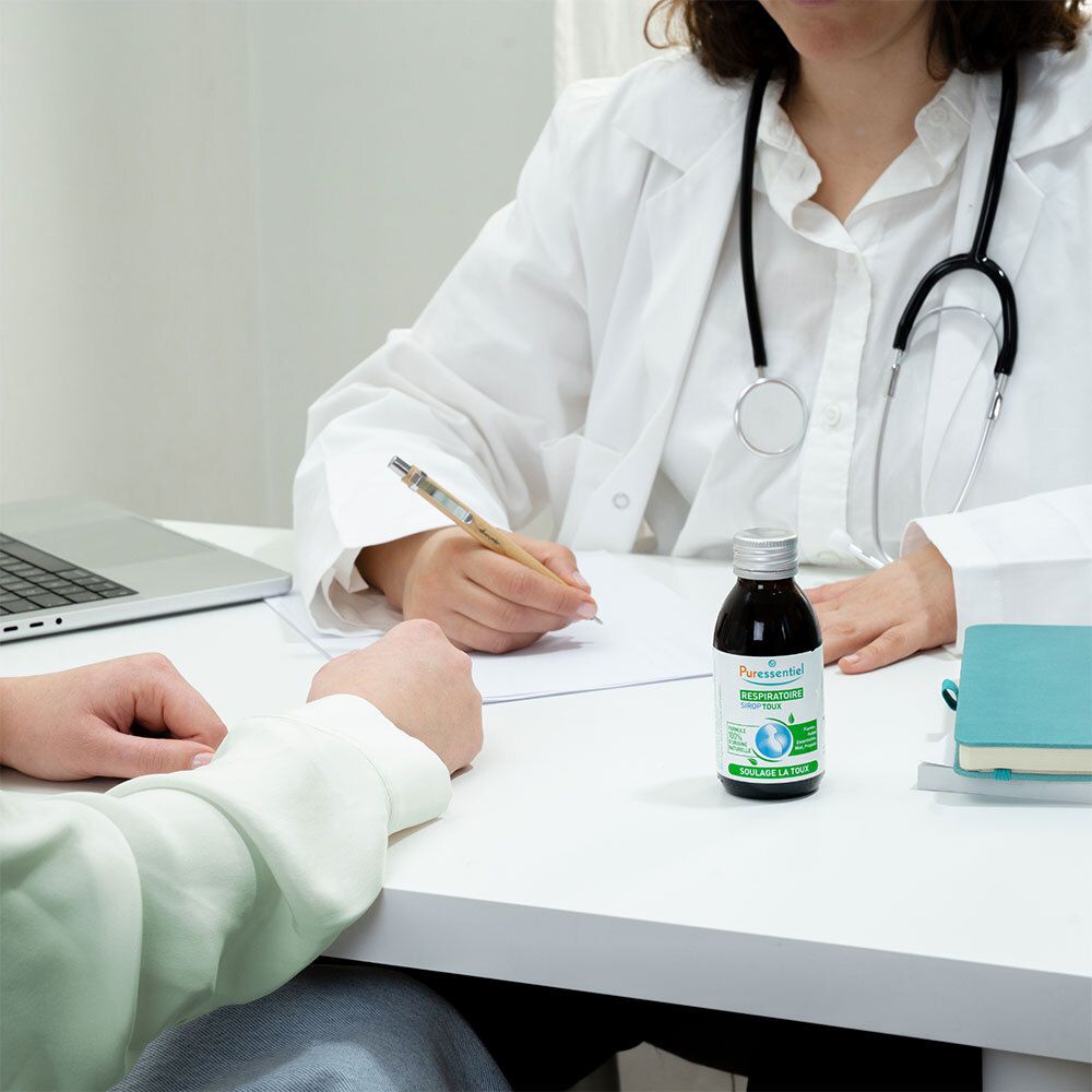 Médecin et patient. Sur la table, un flacon. Texte: PURESSENTIEL RESPIRATOIRE SIROP TOUX.