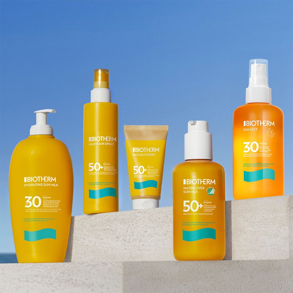 Cinq produits solaires Biotherm sur une marche blanche.