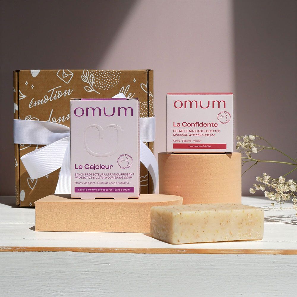 Boîte cadeau OMUM avec savon, crème et boîte à savon, disposés sur des blocs en bois.