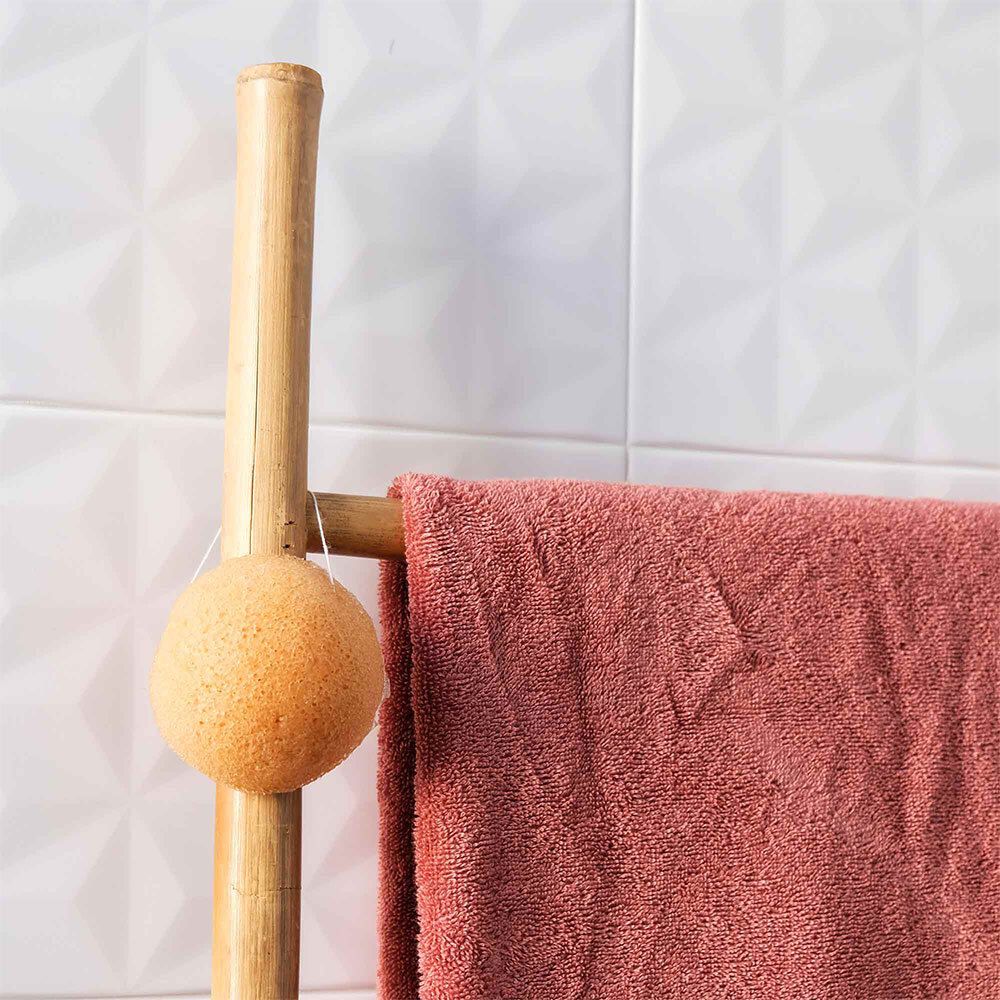 Éponge Konjac avec cordon suspendue à un porte-serviettes.