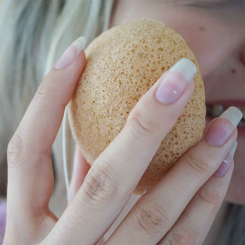 Gros plan d'une main tenant une éponge Konjac.