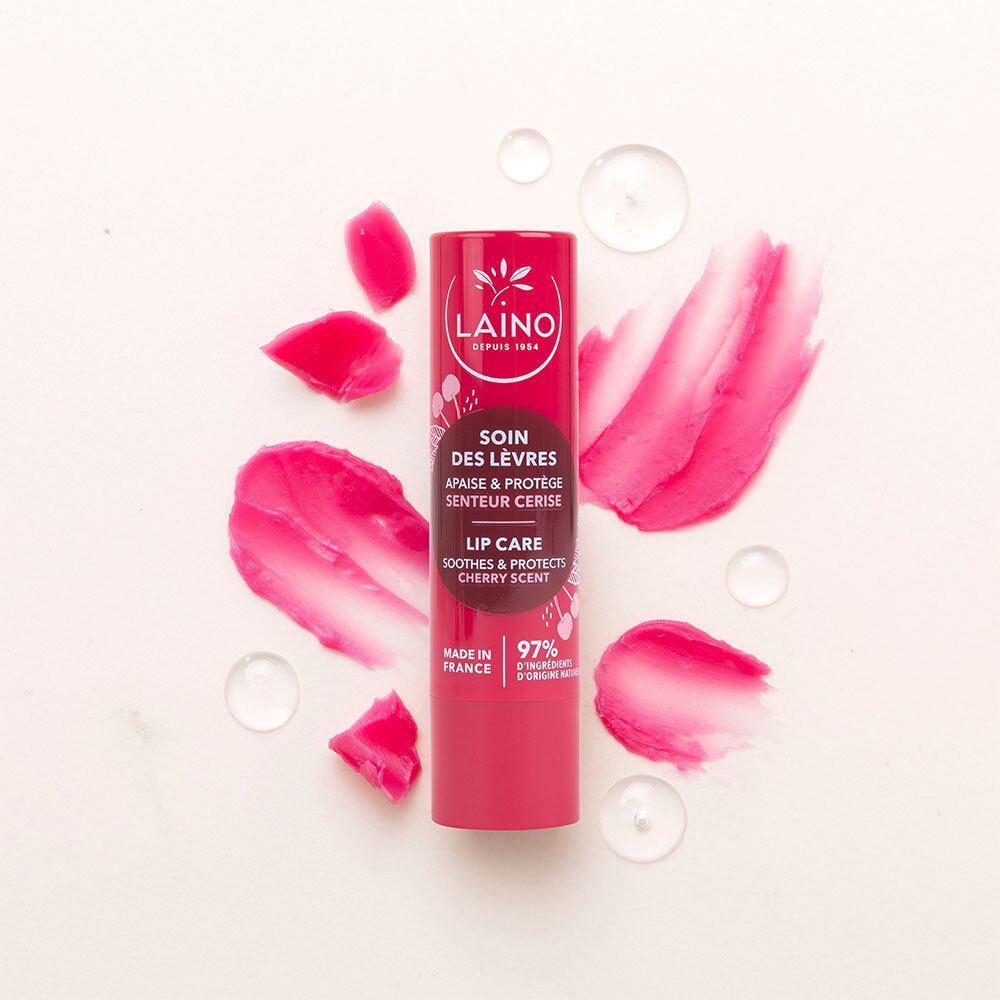 Stick de soin des lèvres rouge avec traces de rouge à lèvres roses et gouttes d'eau sur fond blanc.