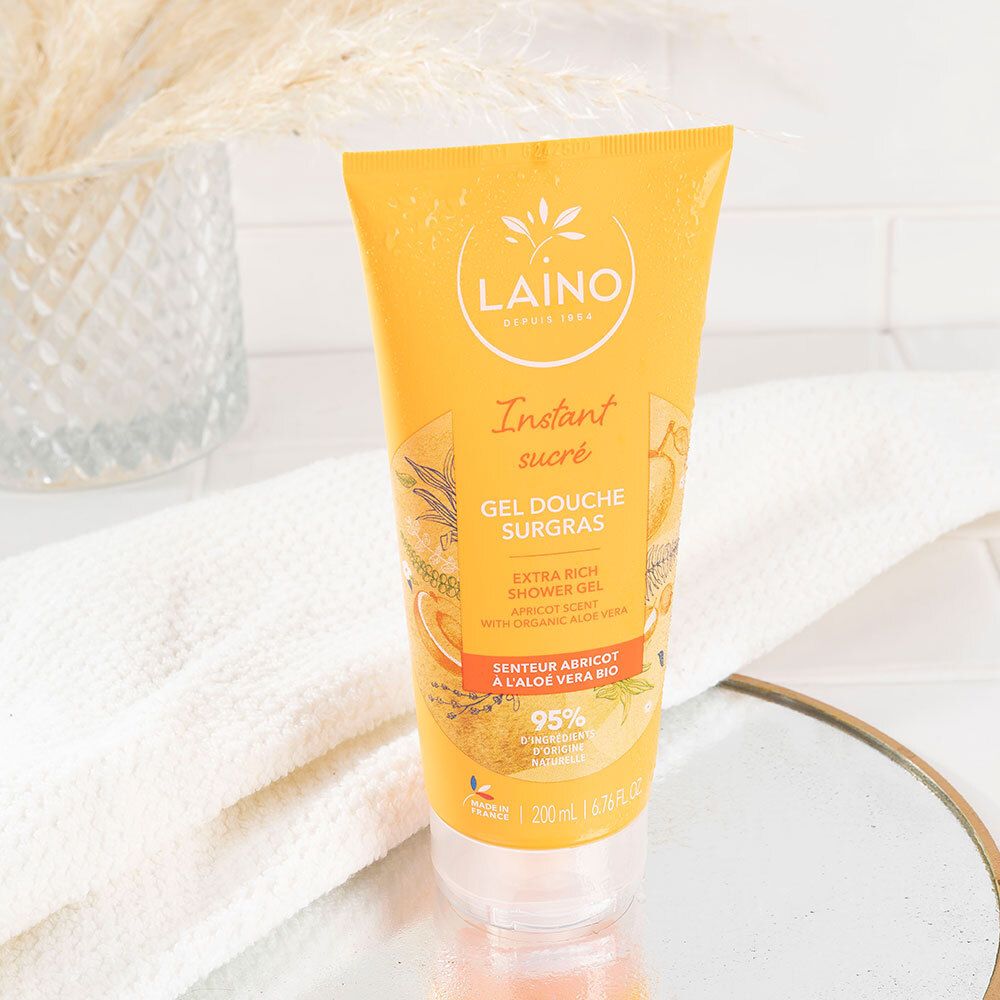 Gel douche surgras hydratant à l'aloé véra bio abricot. Tube jaune sur serviette blanche et miroir.
