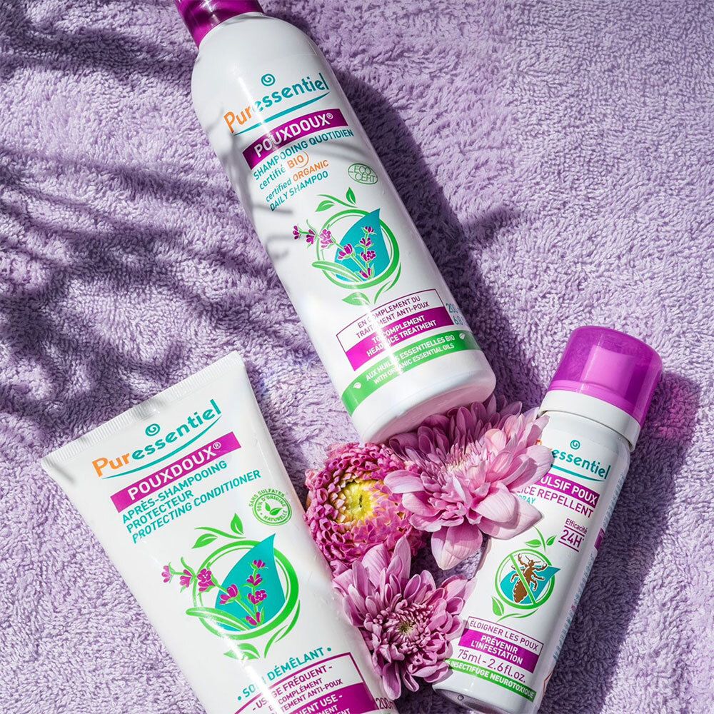 Trois produits : shampooing, après-shampooing et spray. Texte : PouxDoux, Anti-Poux. Fleurs violettes.