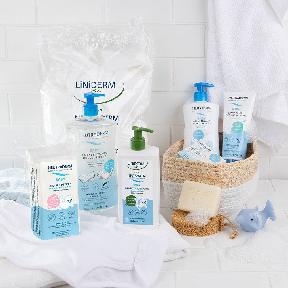 Divers produits Neutraderm Baby. Eau nettoyante, lotion lavante, lingettes. Sur fond blanc. Panier avec accessoires.
