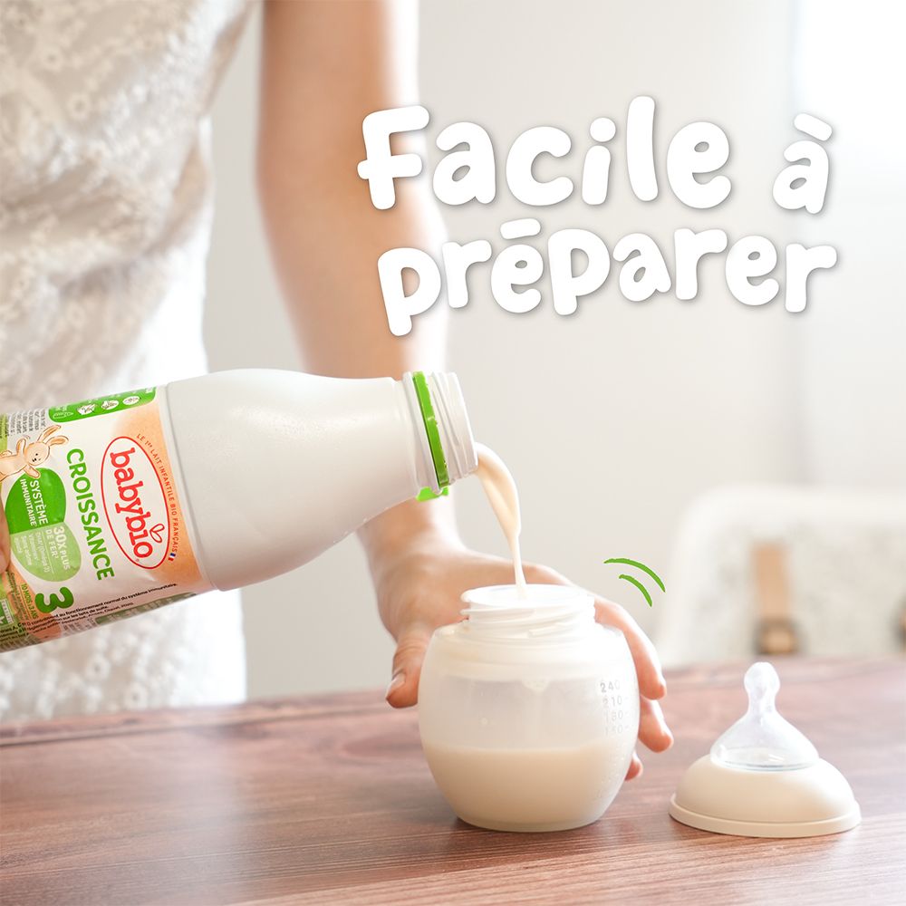 Personne verse du lait d'une bouteille Babybio dans un biberon. Bouchon vert, biberon avec tétine.