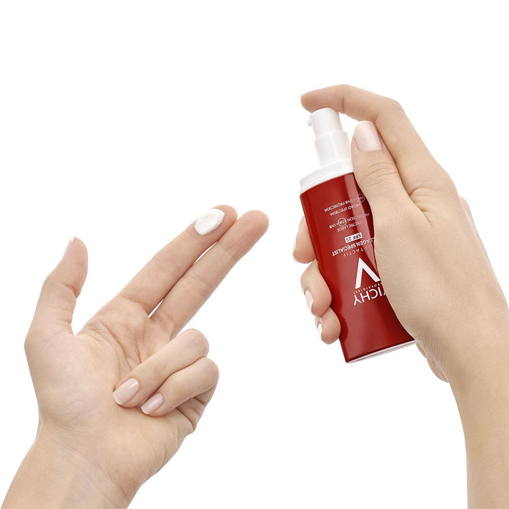 Mains avec produit. Crème sur doigt. Tube rouge avec pompe blanche.