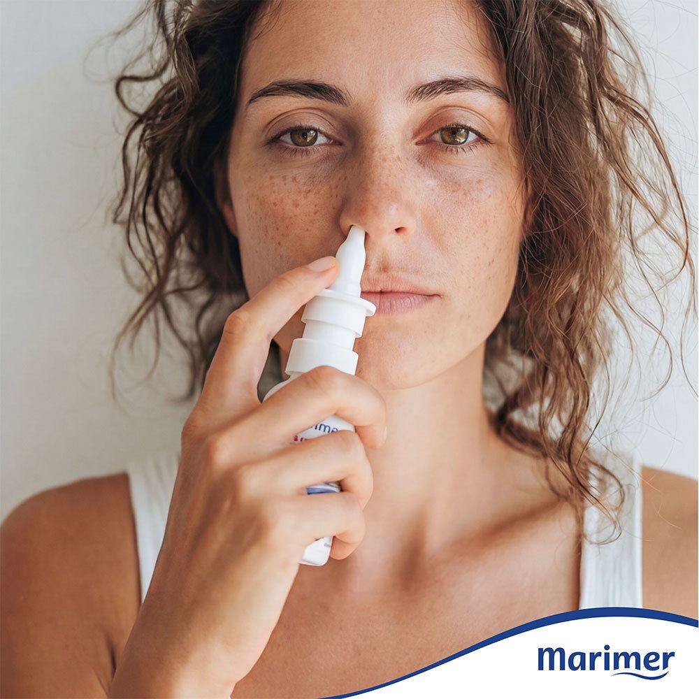 Femme utilisant un spray nasal Marimer. Flacon blanc avec embout. Marque Marimer en bas à droite.