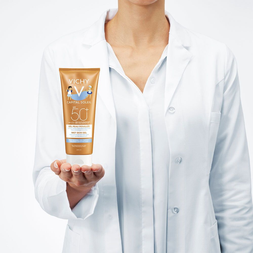 Personne en blouse blanche tenant un tube de crème solaire. Inscriptions : VICHY, Capital Soleil, SPF 50+.
