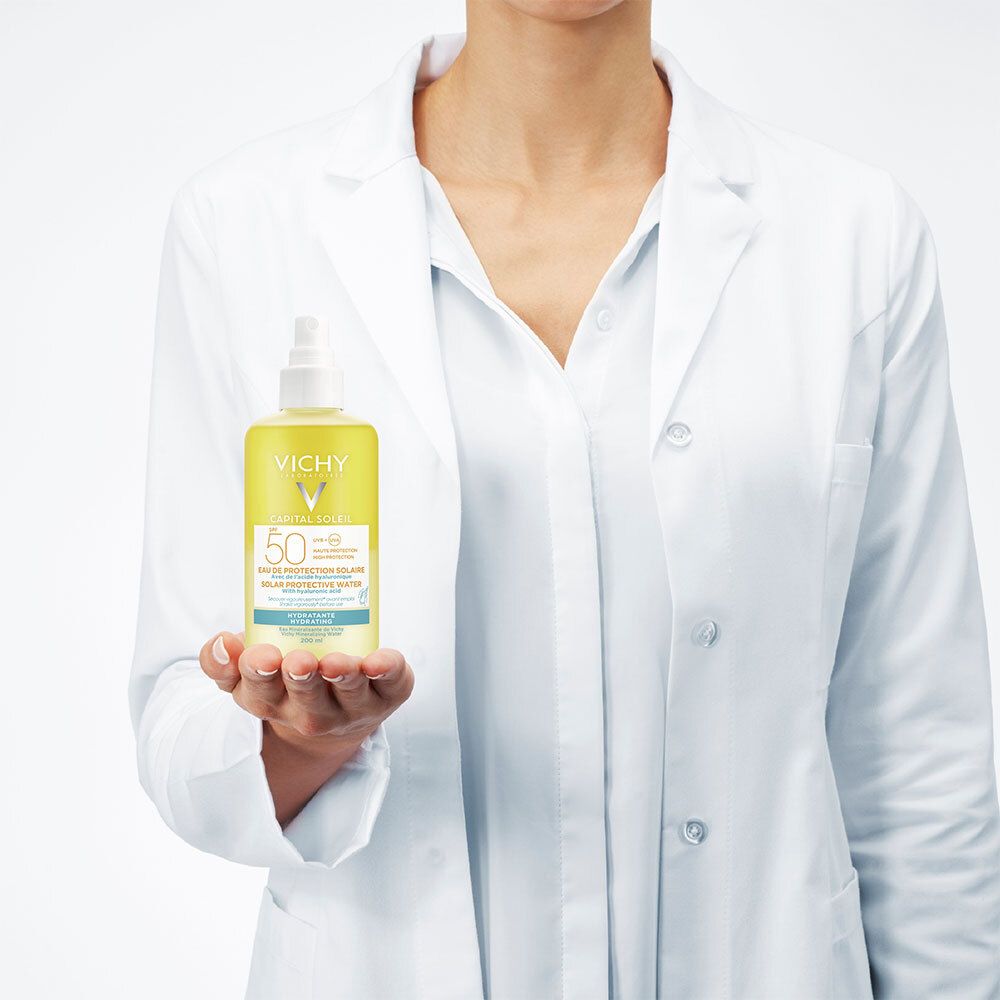 Personne en blouse blanche tenant Vichy Capital Soleil SPF 50. Flacon jaune.