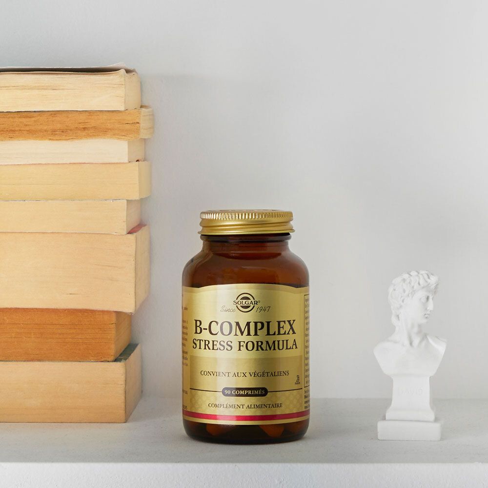 Flacon sur une étagère avec des livres et un buste. Produit : B-Complex Stress Formula.