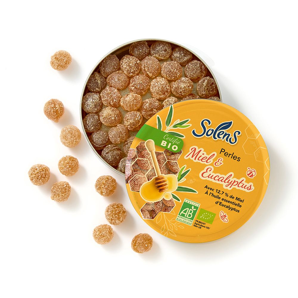 Boîte ouverte de SOLENS Perles Miel & Eucalyptus. Bonbons ronds dorés. Couvercle jaune avec nom du produit et certification bio.
