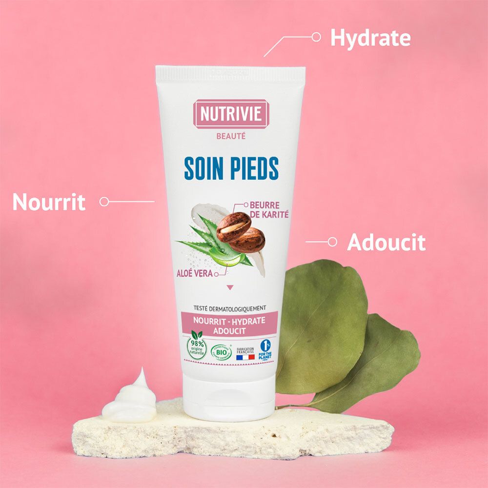 Crème pour les pieds Nutrivie Beauté Soin Pieds sur une pierre, avec mousse et feuilles, mettant en évidence la nutrition, l'hydratation et l'adoucissement.