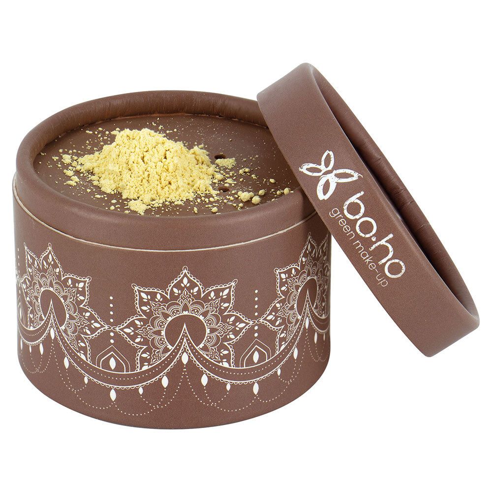 Boîte ronde marron ouverte avec poudre jaune. Couvercle avec logo et texte. Motif décoratif sur la boîte.
