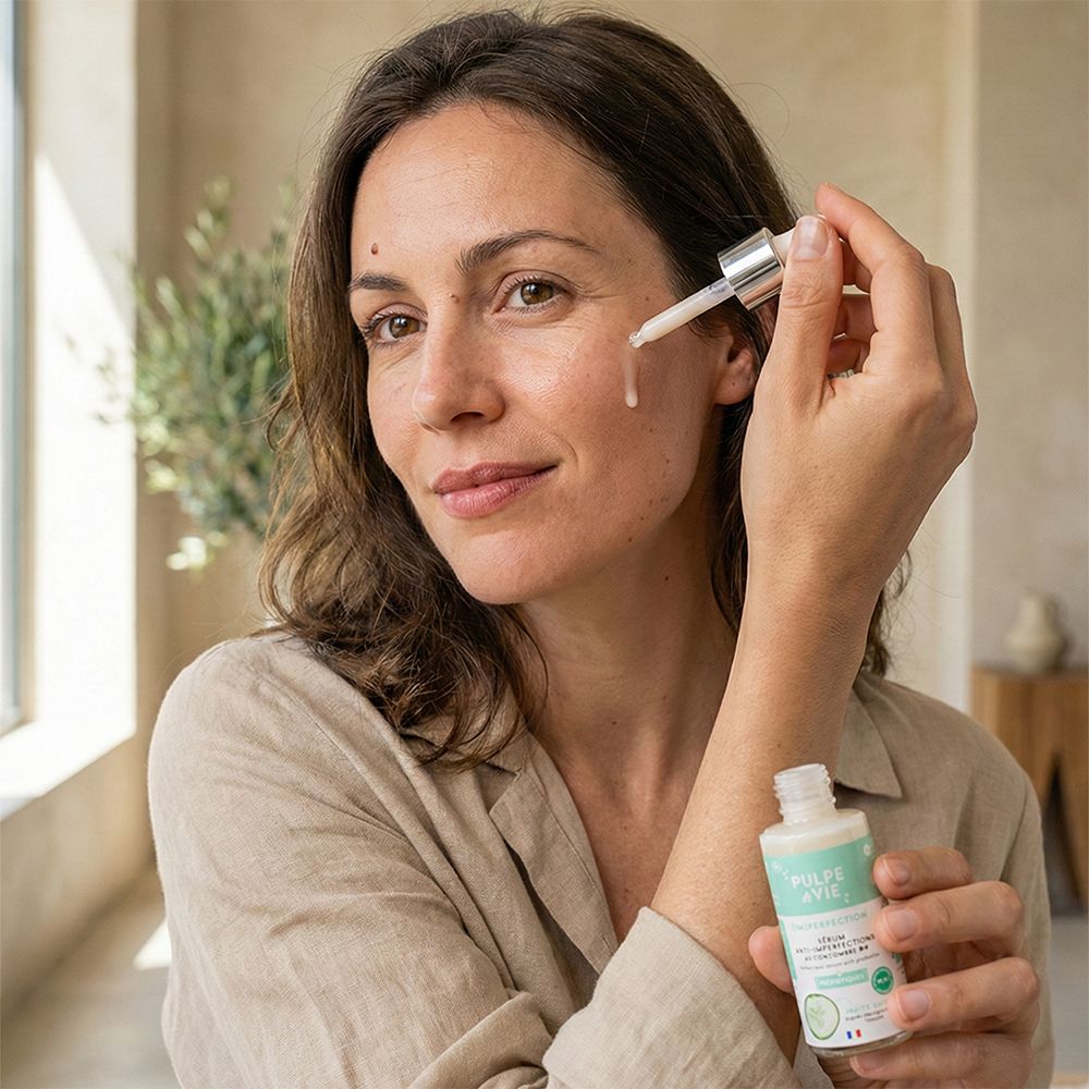 Femme tenant un flacon. Elle applique le produit sur son visage. Flacon avec étiquette. Pipette.