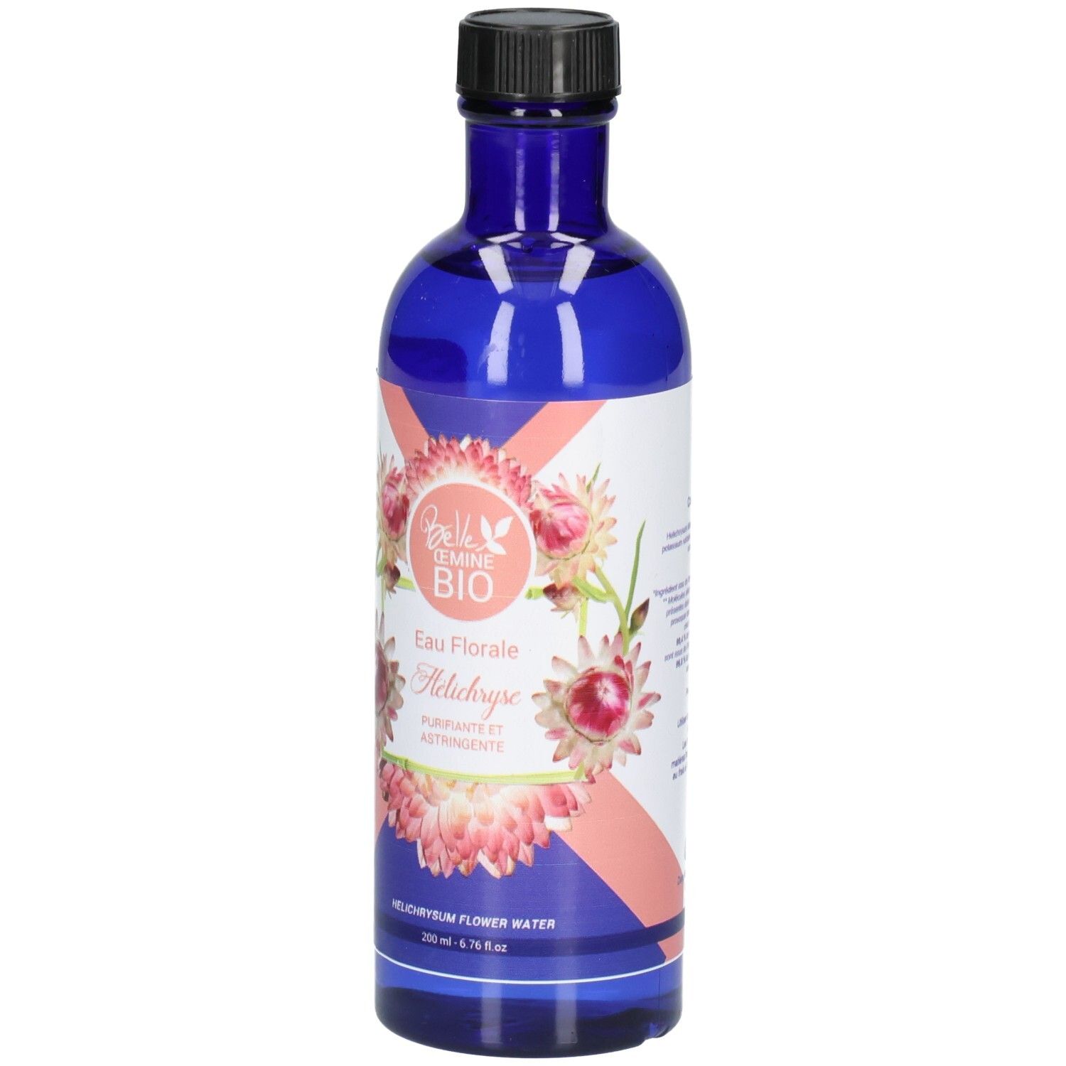Flacon en verre bleu avec bouchon noir, étiquette ornée de fleurs roses et blanches et de texte.