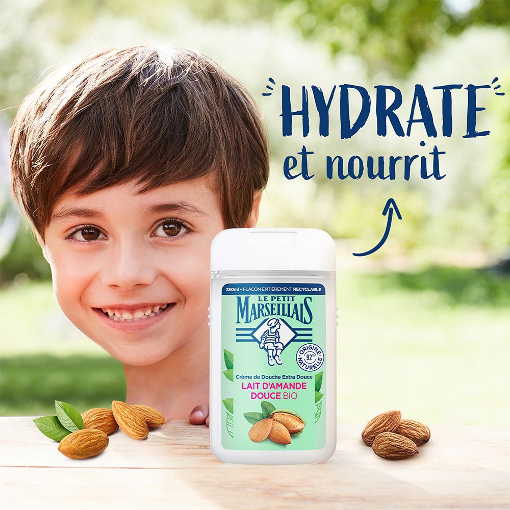 Enfant avec flacon de gel douche. Texte: Hydrate et nourrit. Marque: Le Petit Marseillais. Inscription: Lait d'Amande Douce Bio. Amandes.