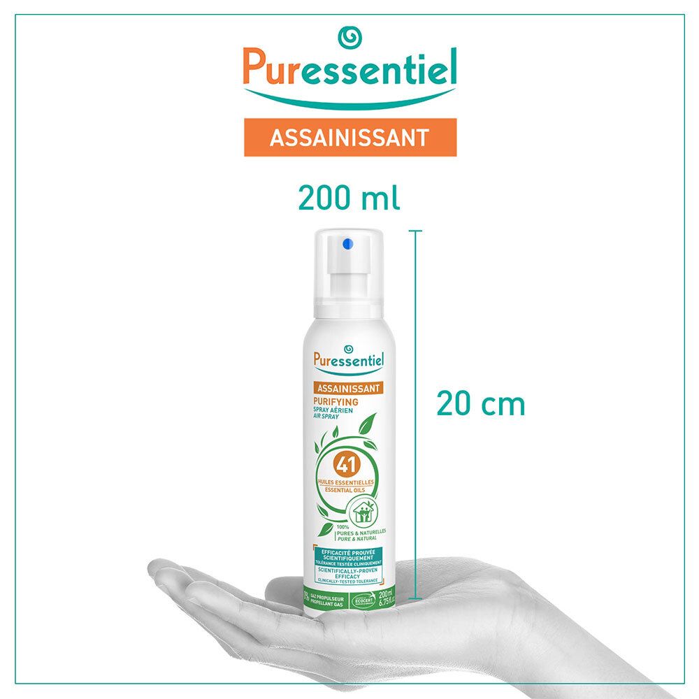 Flacon spray blanc avec étiquette orange et verte. Texte : ASSAINISSANT, 200 ml, 20 cm de haut. Main tenant le flacon.