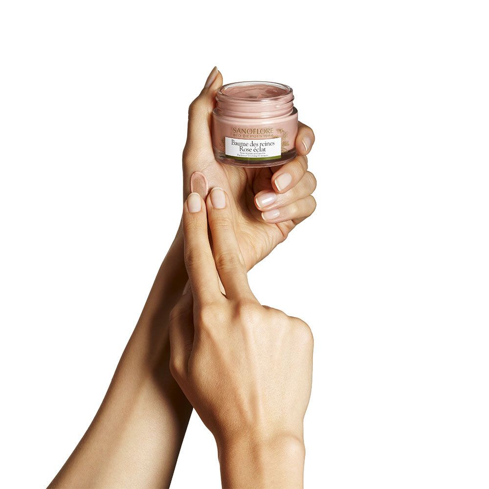Mains tenant un pot de crème. SANOFLORE, Baume des reines Rose éclat. Crème rose. Label bio.
