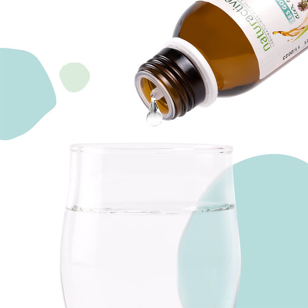 Liquide versé dans un verre d'eau. Flacon brun, bouchon blanc. Naturactive Les Gouttes aux Essences.
