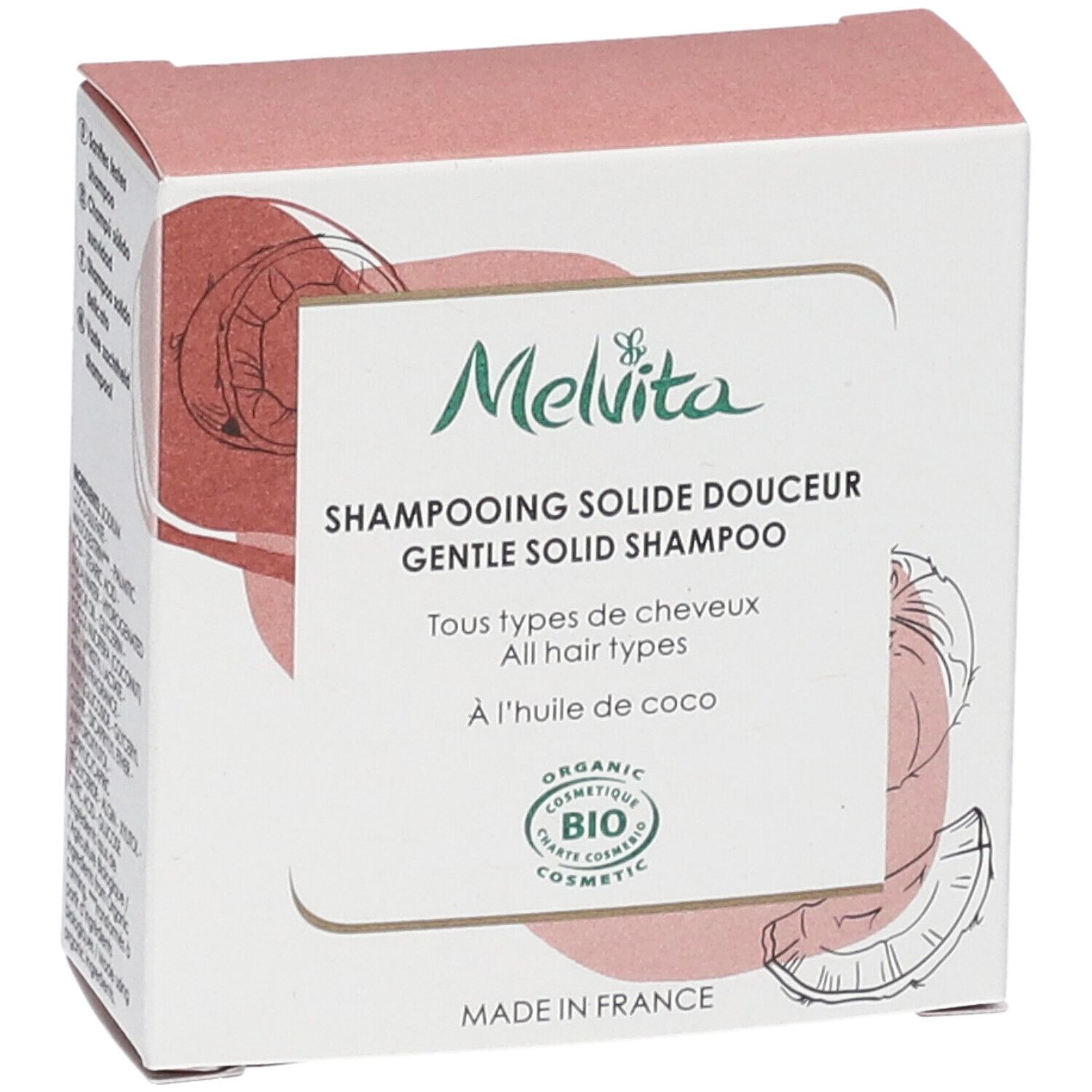 Vue latérale de l'emballage du shampooing. Texte : "Melvita", "Shampooing solide douceur", "BIO COSMETIC". Illustration noix de coco.