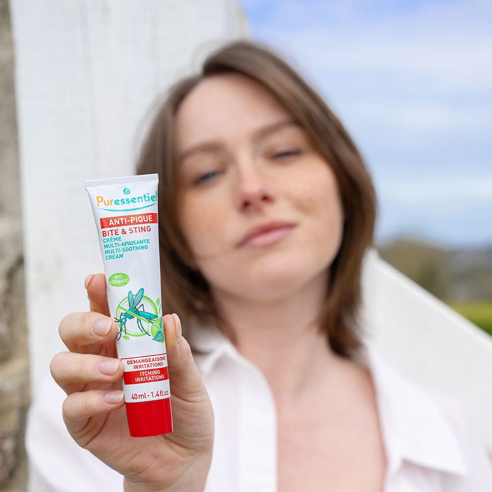 Femme tenant un tube de crème. Inscription : Anti-Pique, crème multi-apaisante. Certification bio.