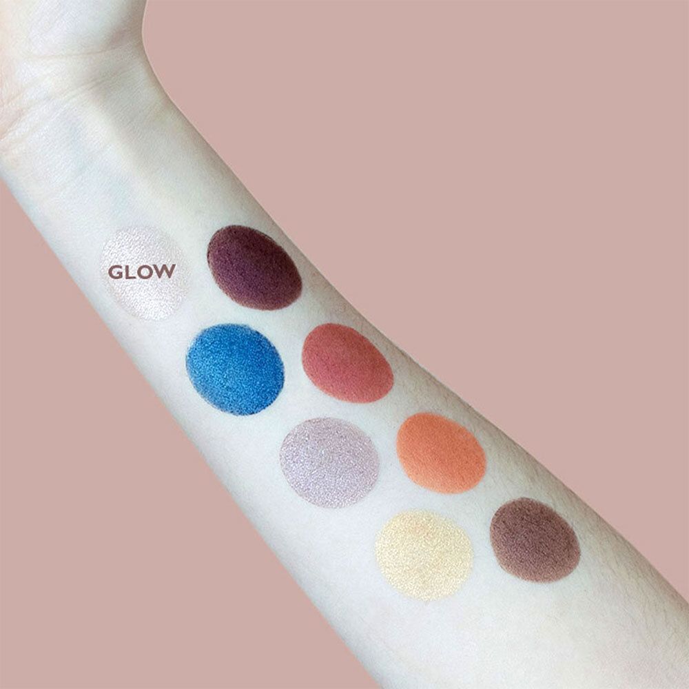Bras avec échantillons de fard à paupières. Différentes couleurs en ronds. Inscription 'GLOW'. Nom du produit non visible.