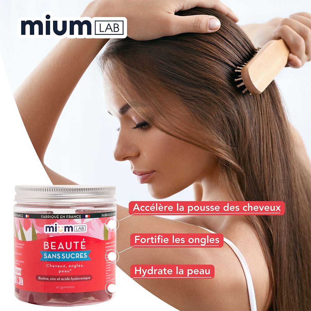 Femme se coiffant. Pot de gummies à côté. Inscription : mium LAB, Beauté sans sucres. Texte : Accélère la pousse, fortifie les ongles, hydrate la peau.