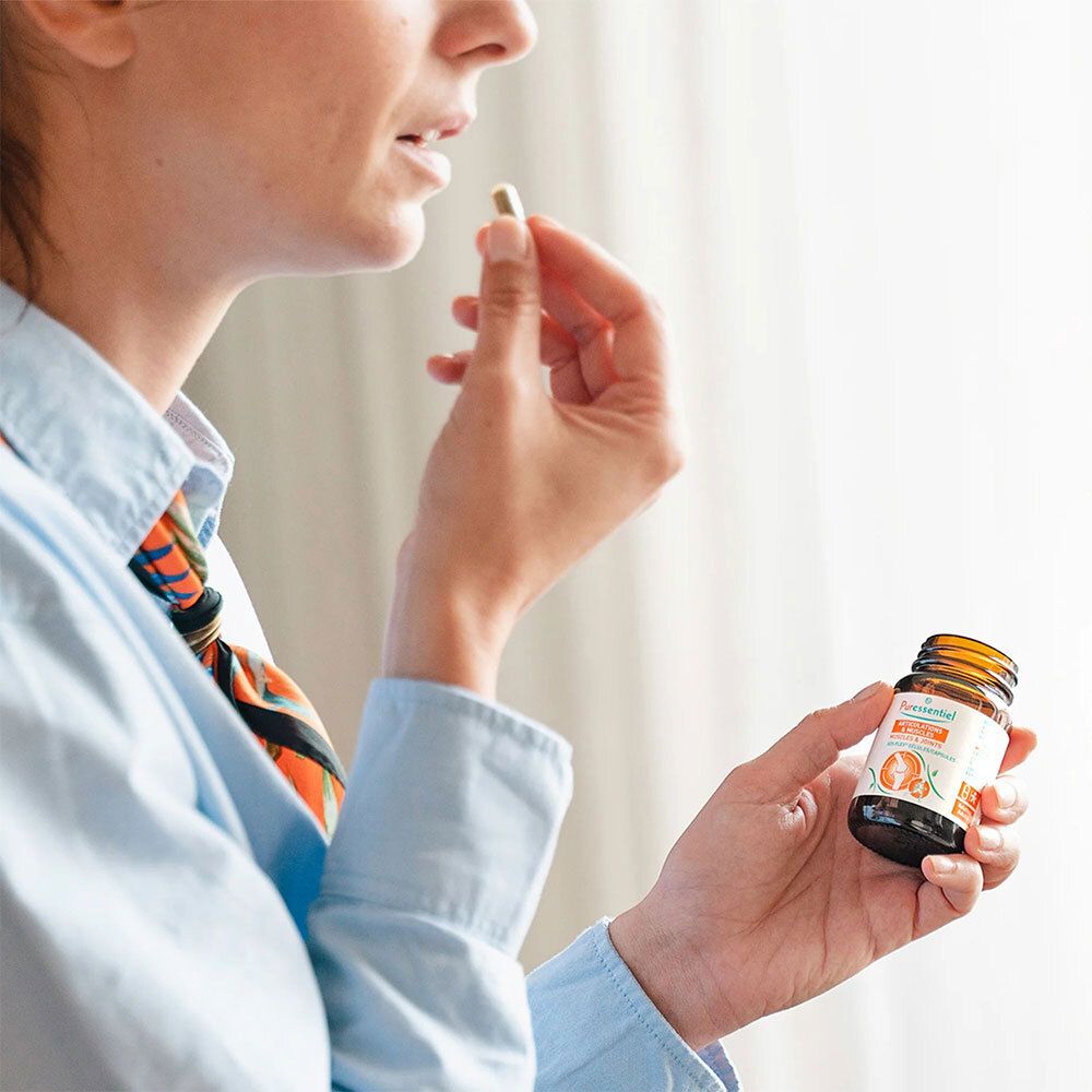 Femme tenant un flacon et une gélule. Articulations & Muscles SOS FLEX® Gélules. Complément alimentaire.