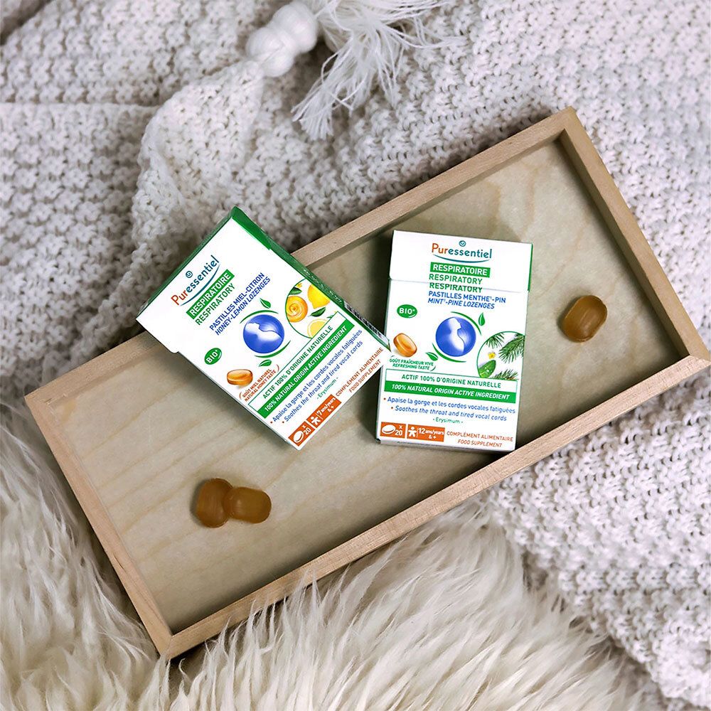 Deux boîtes de pastilles sur un plateau en bois. Pastilles jaunes à côté. Inscription : RESPIRATOIRE.