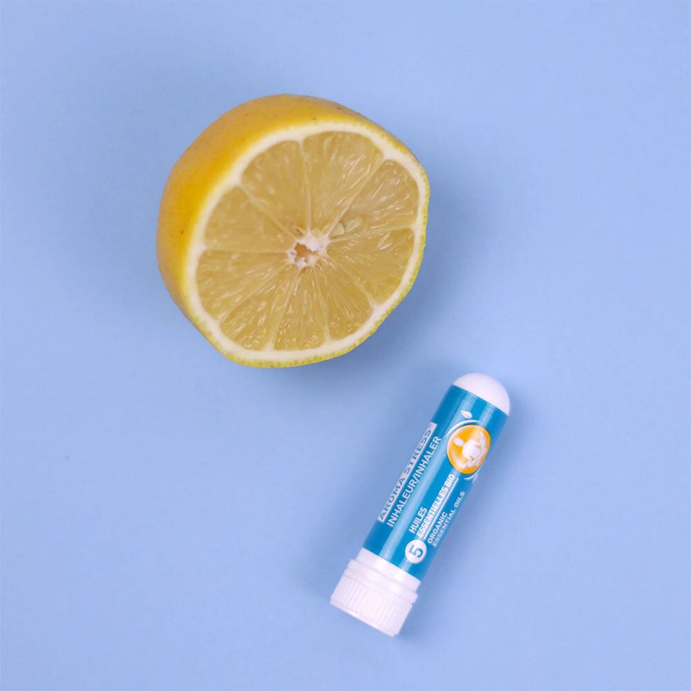 Un inhalateur Puressentiel AROMA STRESS® à côté d'un demi-citron. Inscription : AROMA STRESS® Inhaler/Inhalateur.