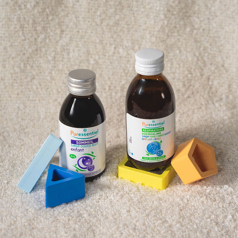 Deux flacons de sirop et jouets. Inscription: SOMMEIL et RESPIRATOIRE. Sur le tapis.