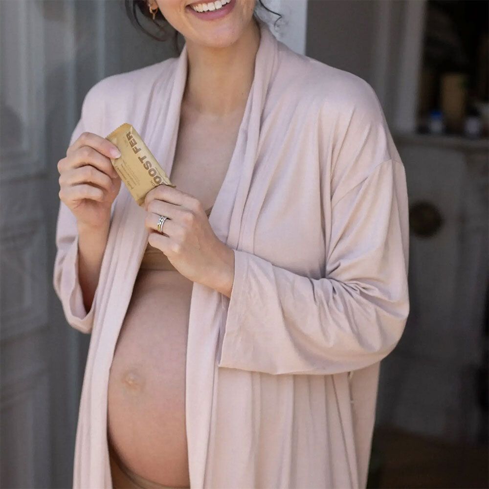 Femme enceinte tenant un petit emballage rectangulaire. Inscription : « BOOST FER ».