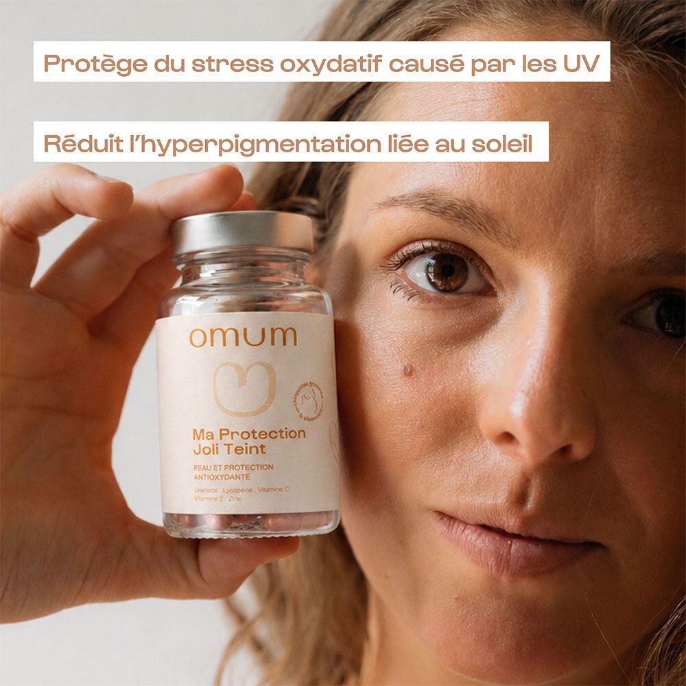 Femme tenant une gélule Omum Ma Protection Joli Teint. Protège du stress oxydatif UV.