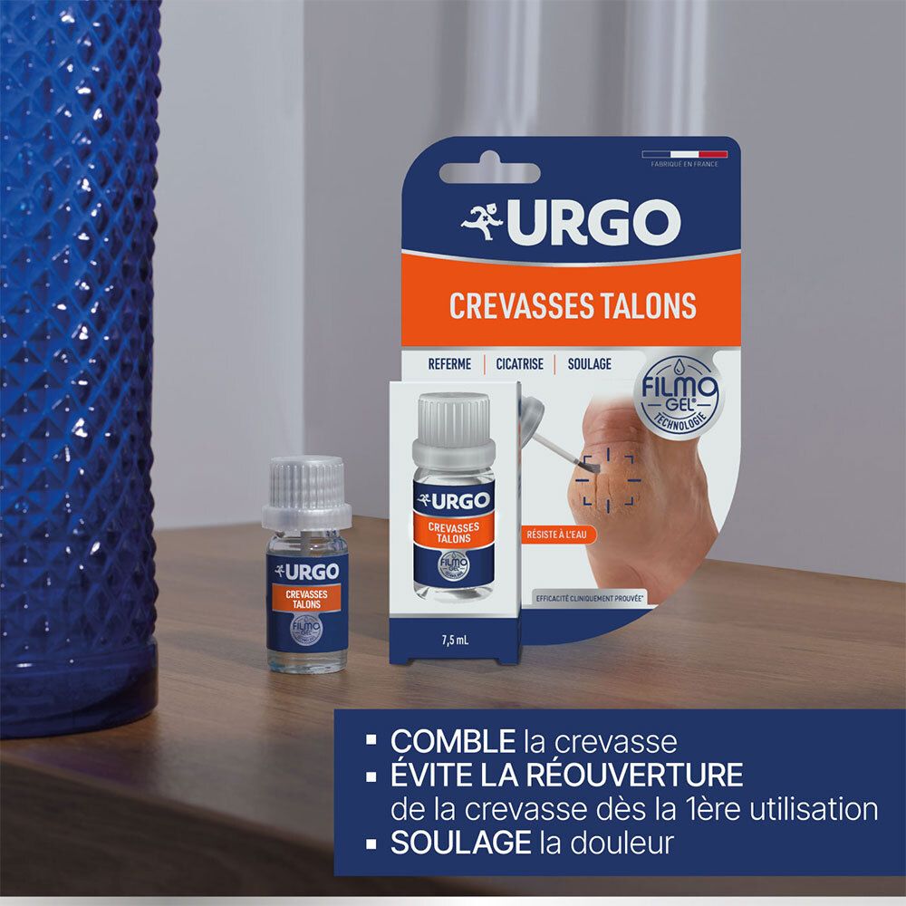 Emballage produit et flacon. Inscription: URGO, Crevasses Talons, Filmogel. Flacon près d'un vase bleu.