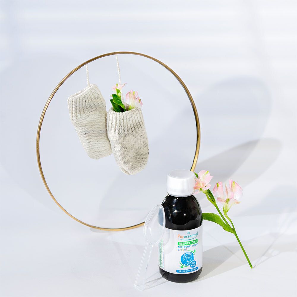 Flacon de liquide brun, cuillère et chaussettes dans un cercle doré. Inscription: Puresentiel Acti Pure.