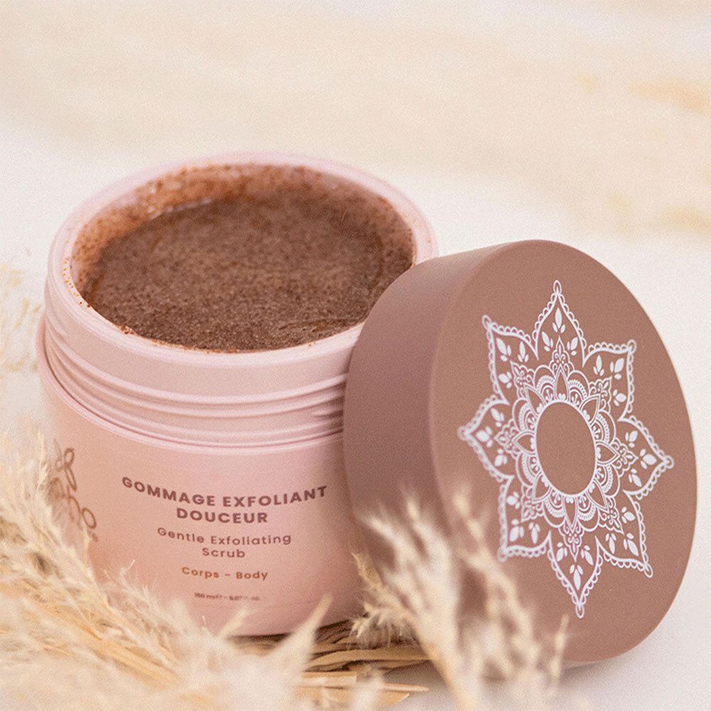 Récipient rose ouvert avec couvercle marron. Le récipient contient un gommage. Le couvercle affiche un motif. Logo: Boho green skincare.